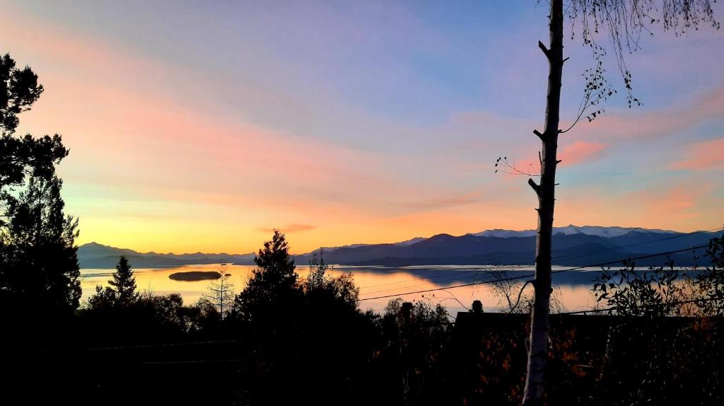 um pôr-do-sol sobre um lago com montanhas ao fundo em Casa Bosque em San Carlos de Bariloche