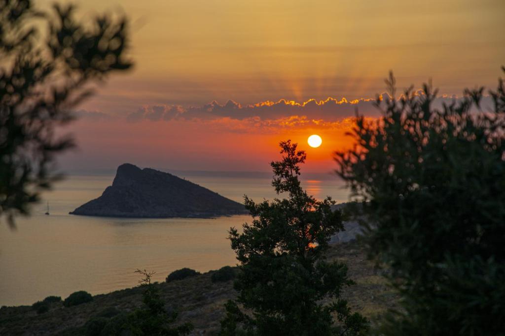 zachód słońca nad oceanem z drzewami na pierwszym planie w obiekcie Goknar Knidos Oasis Nature Hotel w mieście Datça