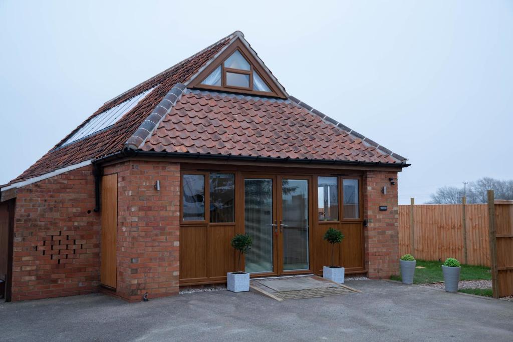 a small red brick house with a roof at The Fern at BrackenXcapes in Newark-on-Trent