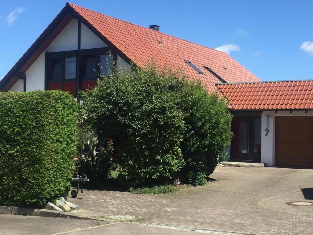 a house with a red roof and two bushes at Ferienwohnung Plettenbergblick in Dotternhausen