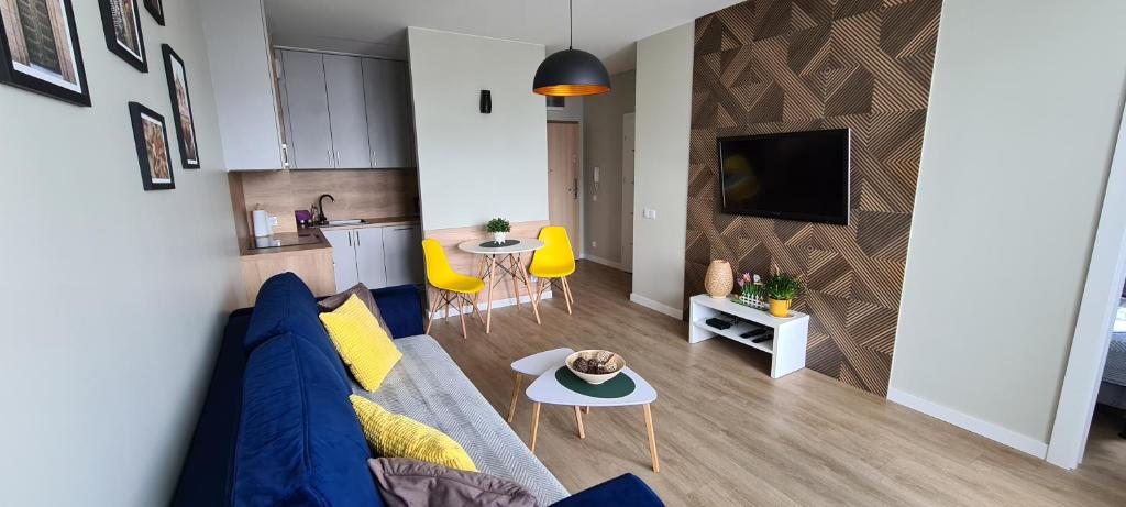Il comprend un salon avec un canapé bleu et une cuisine. dans l'établissement APARTAMENT SORENTO 28, à Gorzów Wielkopolski