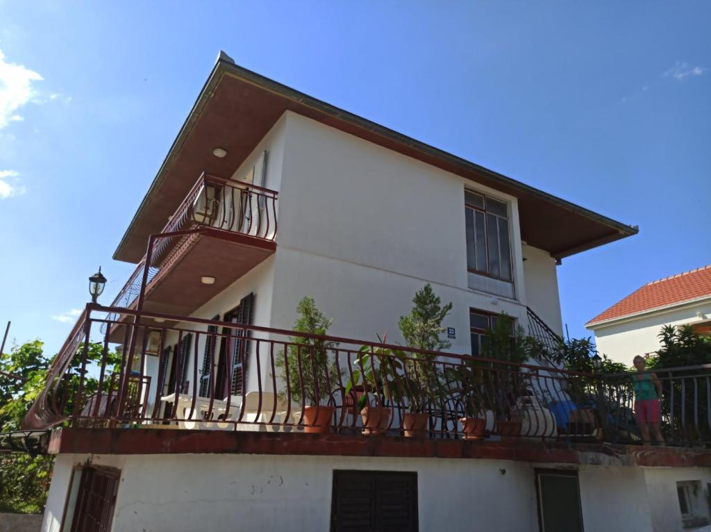 ein weißes Haus mit einem Balkon mit Topfpflanzen in der Unterkunft Apartman Krivokapic in Igalo