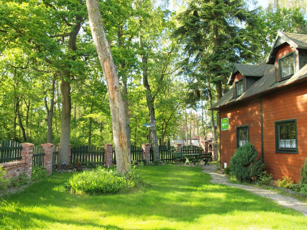 a house in a yard with a bench in the grass at Domki Klara in Pobierowo