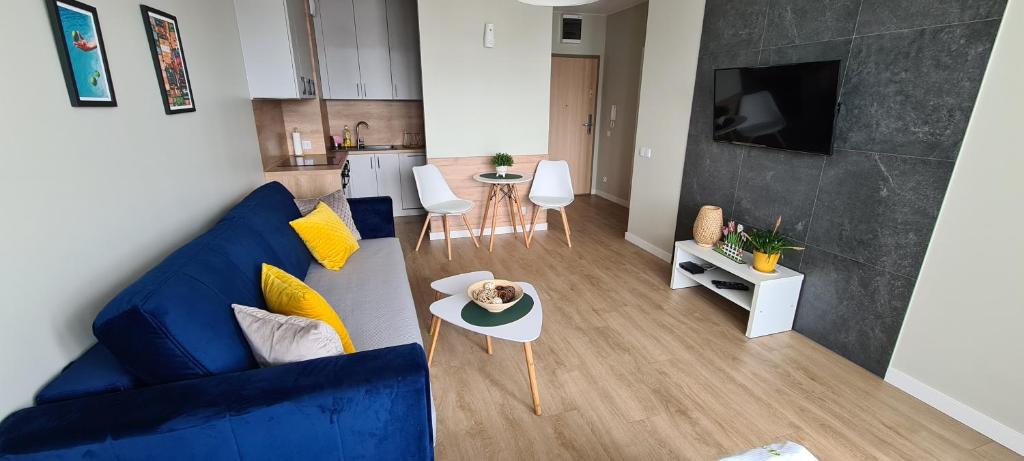 sala de estar con sofá azul y cocina en APARTAMENT SORENTO 27, en Gorzów Wielkopolski