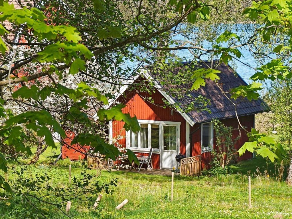 Holiday home in Vreta في Borensberg: منزل احمر صغير مع شرفة وطاولة