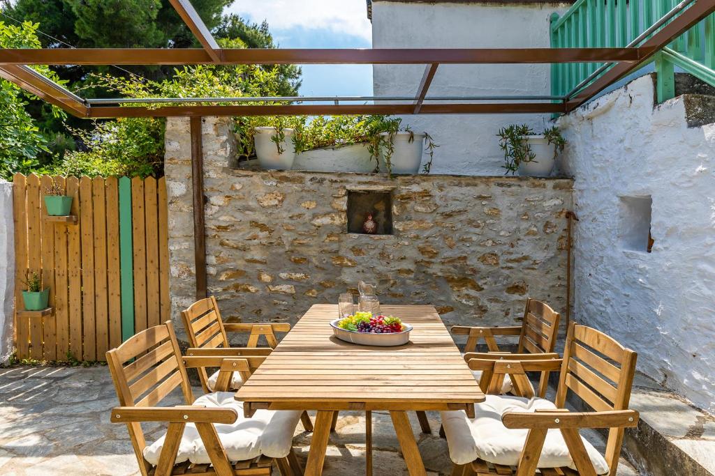 a wooden table with chairs and a bowl of flowers on it at La Belle Merle in Panormos Skopelos