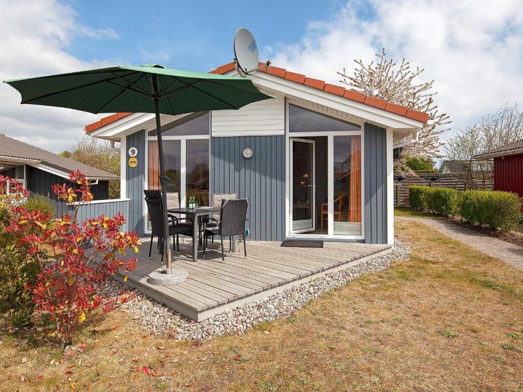 un pequeño cobertizo con una mesa y una sombrilla en 4 person holiday home in GROEMITZ, en Grömitz