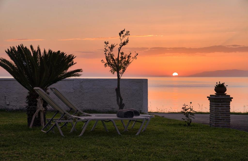 a couple of chairs sitting on the grass with the sunset at Vrachos holiday home in Alikanas