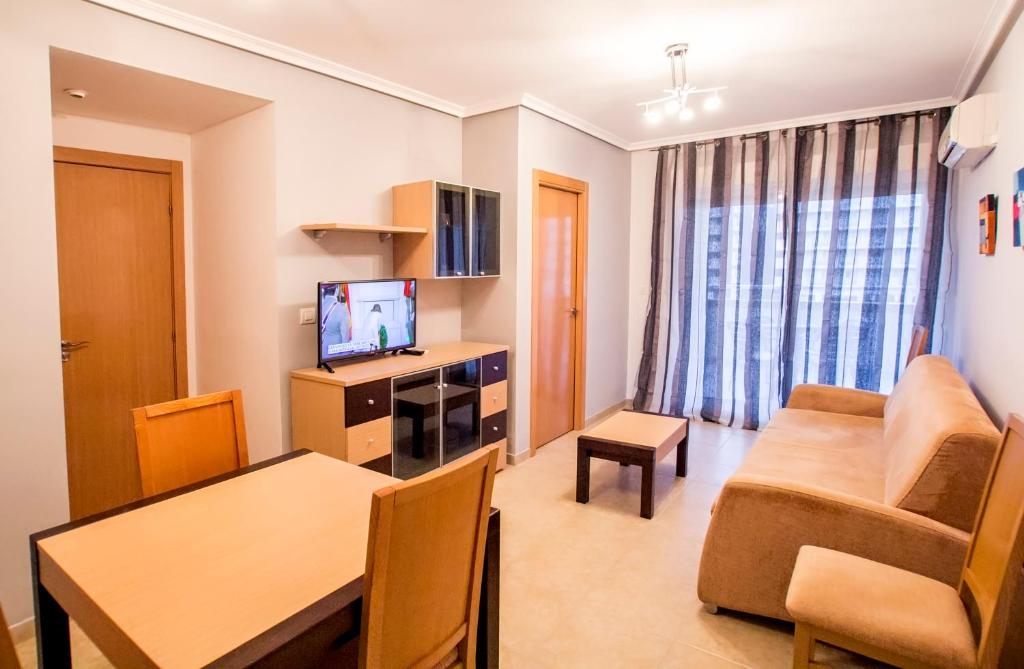 a living room with a couch and a table and a television at Apartamentos Be Suites Mar de Azahar in Oropesa del Mar