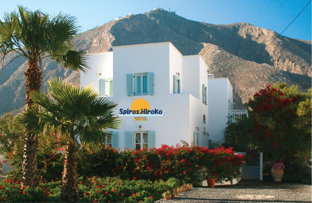 a white building with a palm tree in front of a mountain at SPIROS & HIROKO Hotel - ADULTS ONLY in Perissa