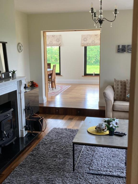 a living room with a fireplace and a table at Burrowlodge in Kilfenora