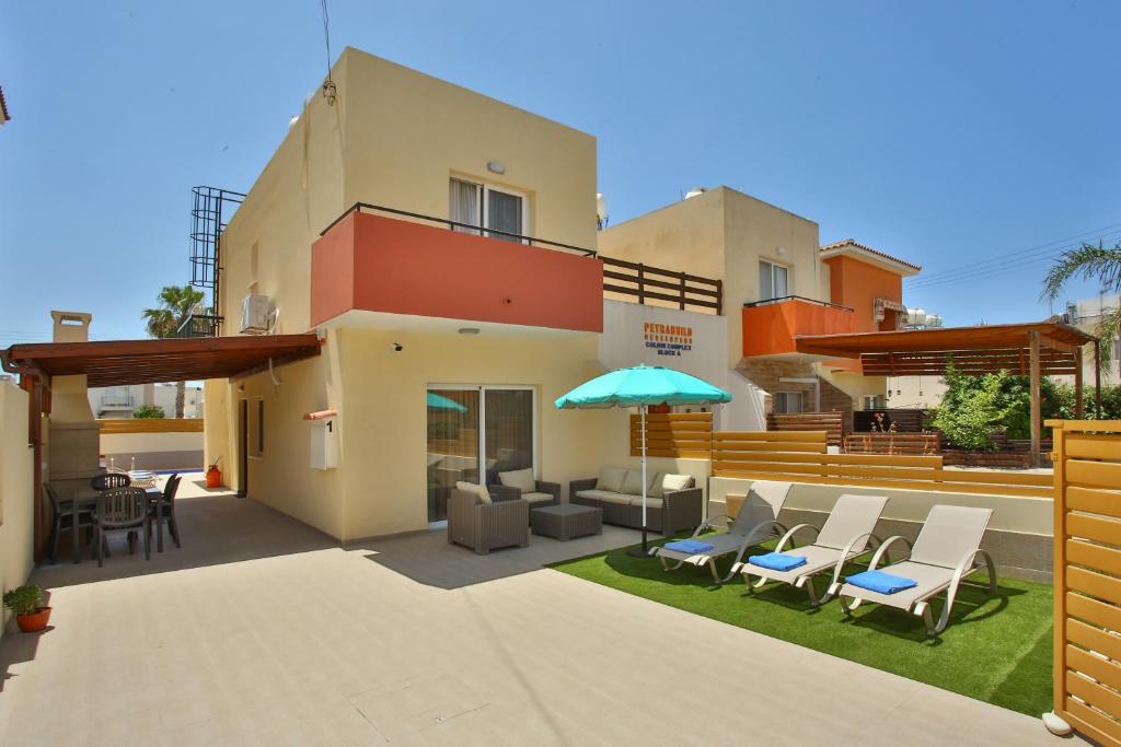 a house with a patio with chairs and an umbrella at Star House in Paphos City