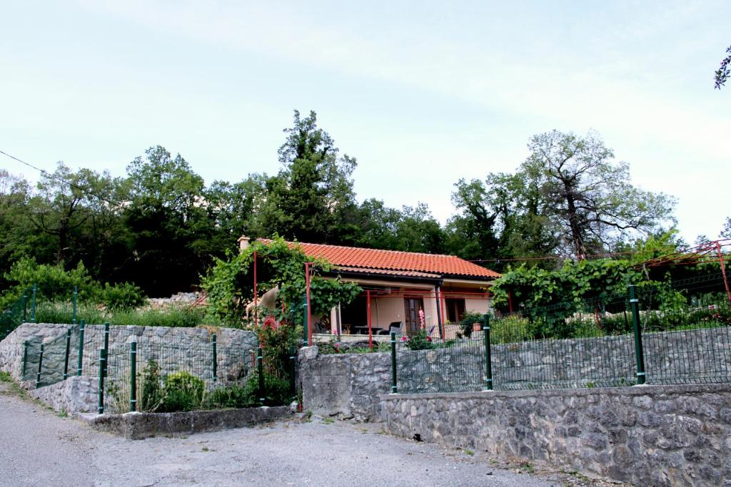 a house behind a stone wall with a fence at Holiday Home Gazevic in Virpazar