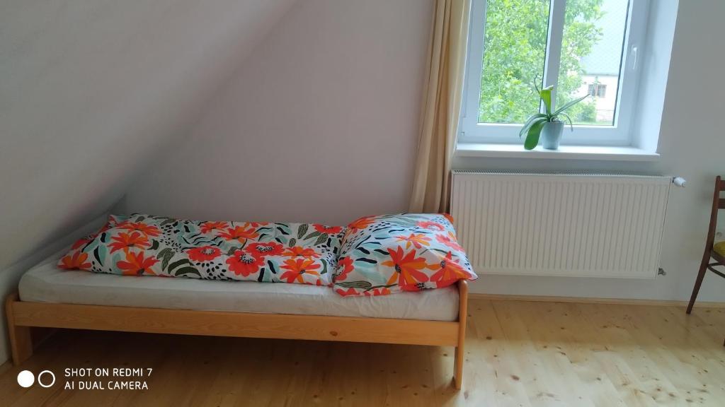 ein kleines Bett in einem Zimmer mit einer Blumendecke in der Unterkunft Ubytovaní V sadu in Stará Červená Voda