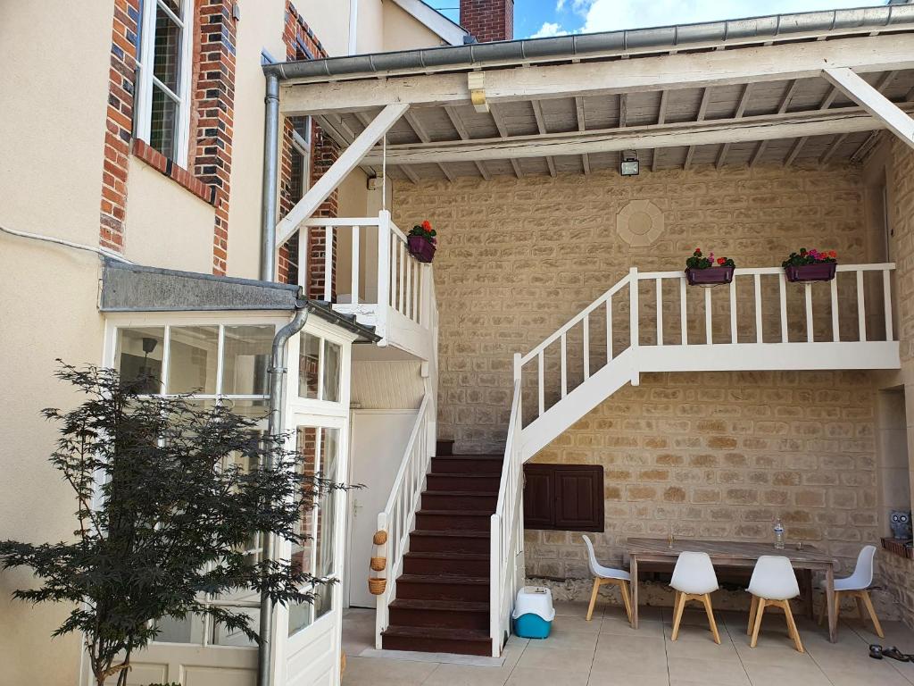 un patio con escalera, mesa y sillas en La Cour des Marotiers en Mareuil-sur-Ay