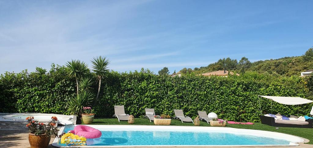 a swimming pool with lounge chairs and an umbrella at Villa la magnifique : piscine , spa , 140m2 in Vailhauquès