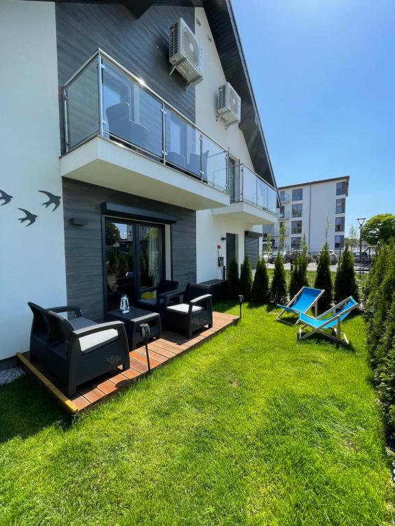 a house with a yard with black furniture on it at Blue Wave Garden in Dziwnówek