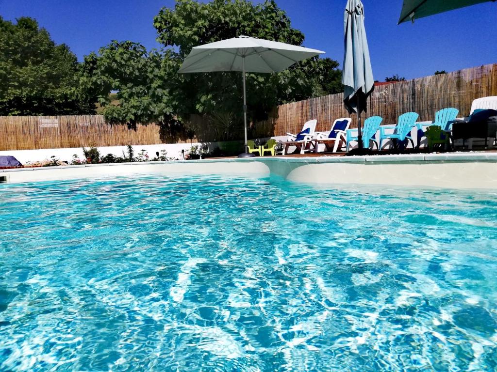 a swimming pool with chairs and an umbrella at A kwaba AD in Brens