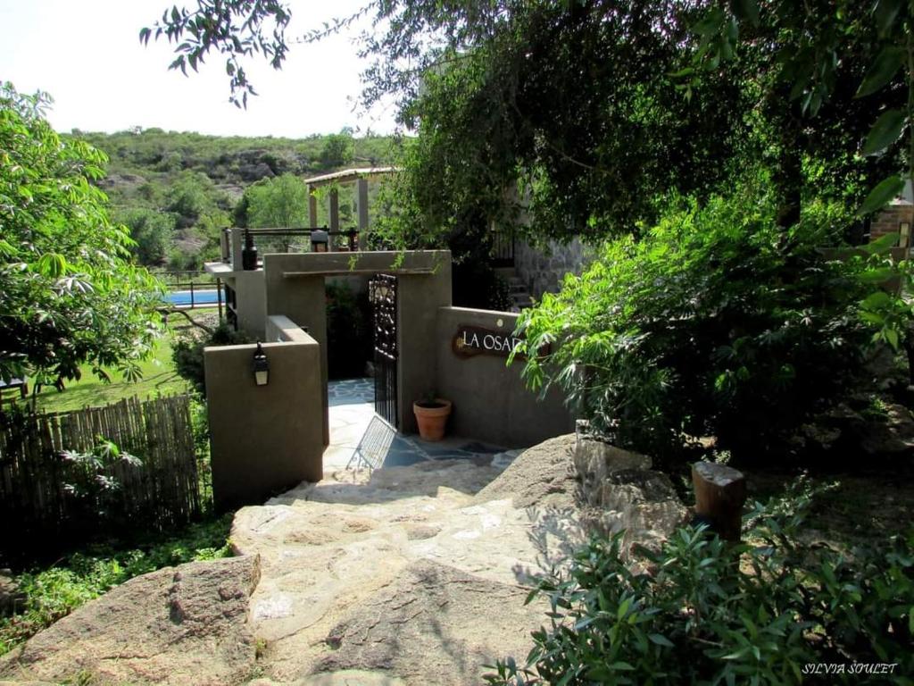 una casa con una puerta y un patio con árboles en La Osadia Cabañas y Suites Solo Adultos en Mina Clavero