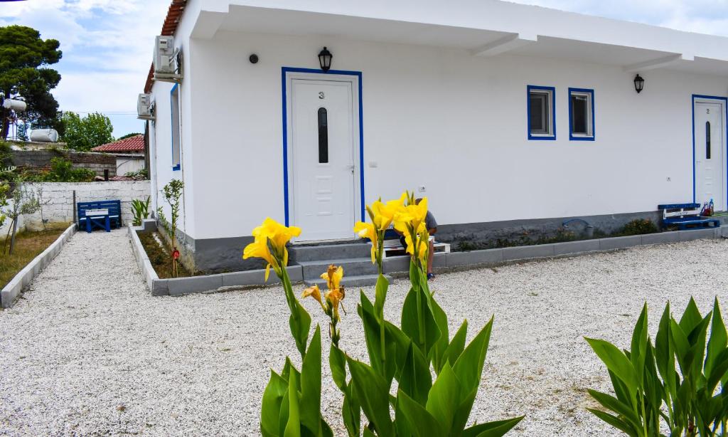 uma casa branca com flores amarelas à frente. em Troi beach house em Vlorë