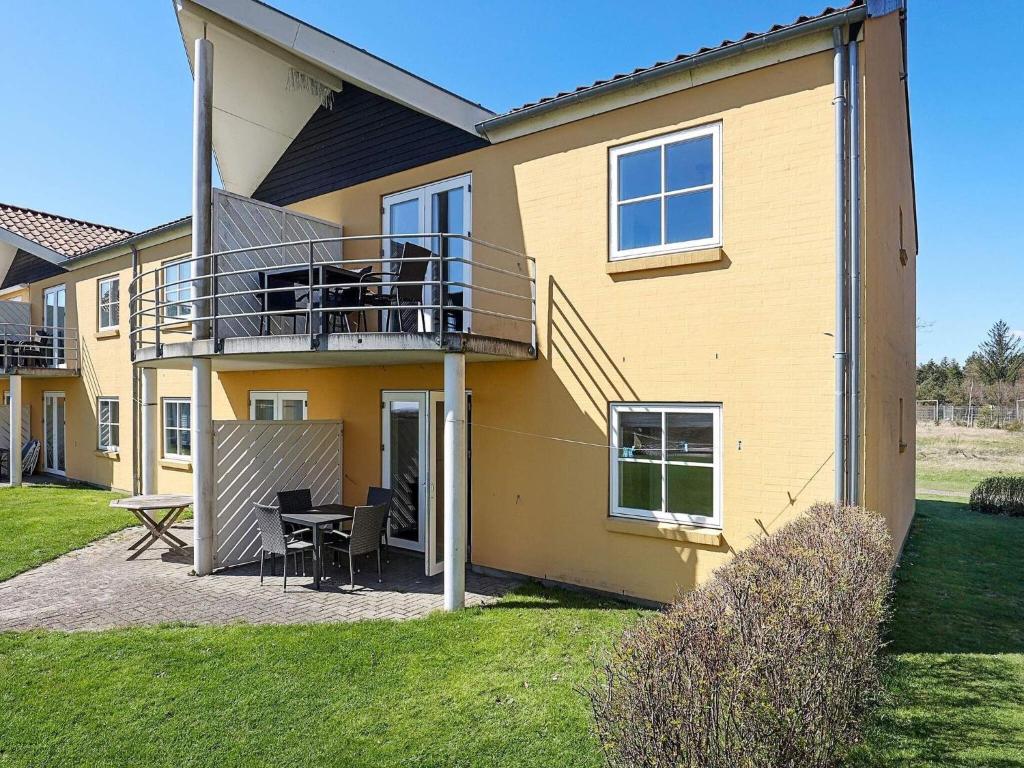 a yellow house with a balcony and a table at Apartment Hals IV in Hals