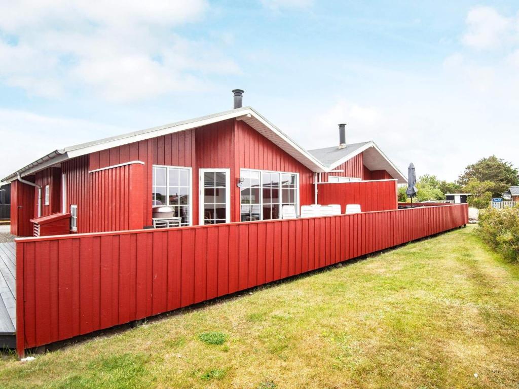 uma casa vermelha com uma cerca vermelha em Three-Bedroom Holiday home in Hvide Sande 2 em Nørre Lyngvig