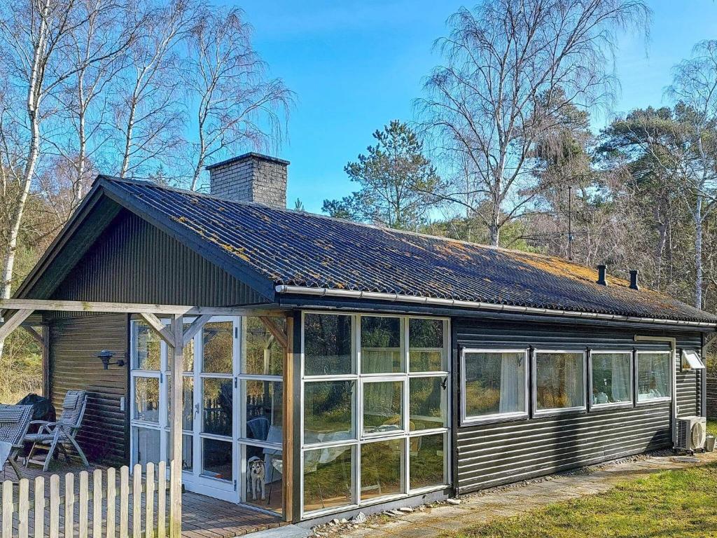 Vester SømarkenにあるTwo-Bedroom Holiday home in Aakirkeby 7の大きな窓とポーチ付きのログキャビン