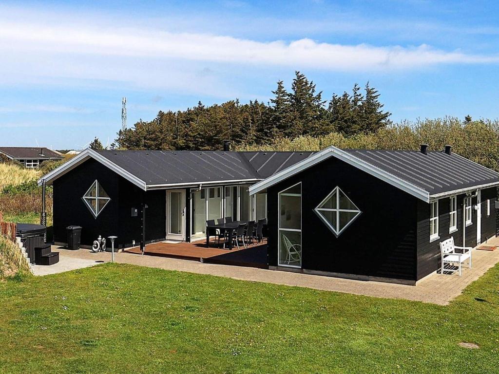 a black house with a porch and a patio at 8 person holiday home in Hirtshals in Hirtshals