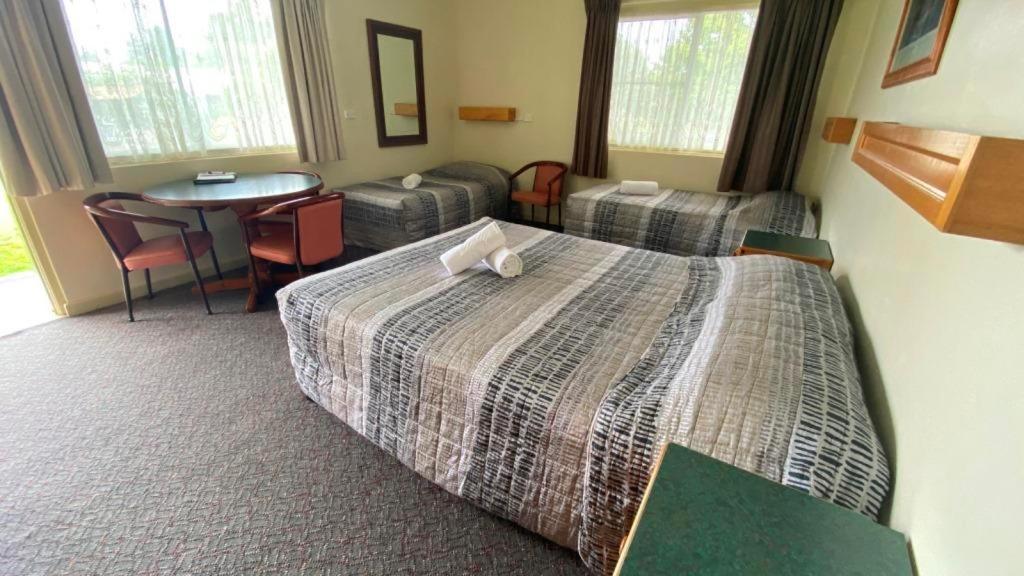 a hotel room with a bed and a table at Bucketts Way Motel Gloucester in Gloucester