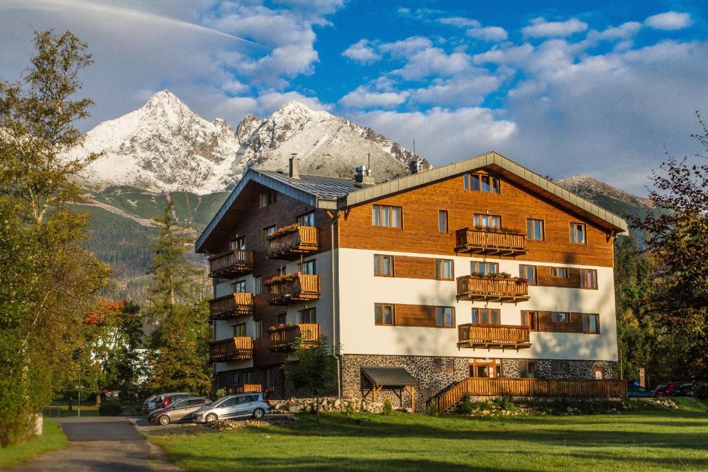 a large apartment building with mountains in the background at Apartmány Bobulky in Tatranská Lomnica