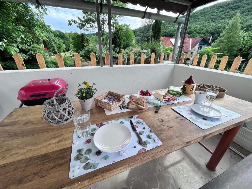 una mesa de madera con platos y platos en un porche en Neve Nincs NYARALÓ, en Balatonfüred