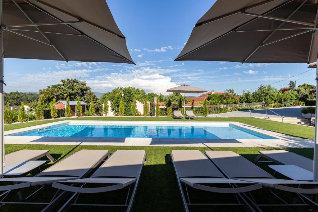 una piscina con sillas y sombrilla en O CERVO CHARM HOUSE, en Vila Nova de Cerveira