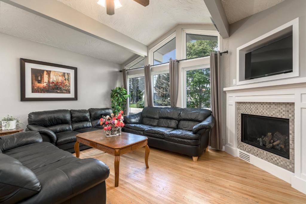 uma sala de estar com mobiliário de couro e uma lareira em D@home Entire house near Glenmore Park em Calgary
