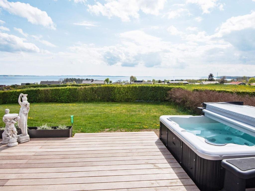 a deck with a hot tub and a swimming pool at 6 person holiday home in R nde in Rønde