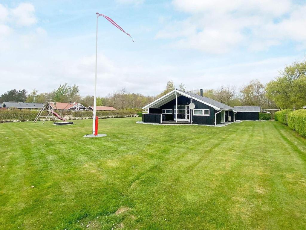 a house in a field with a flag pole at 6 person holiday home in Hemmet in Falen