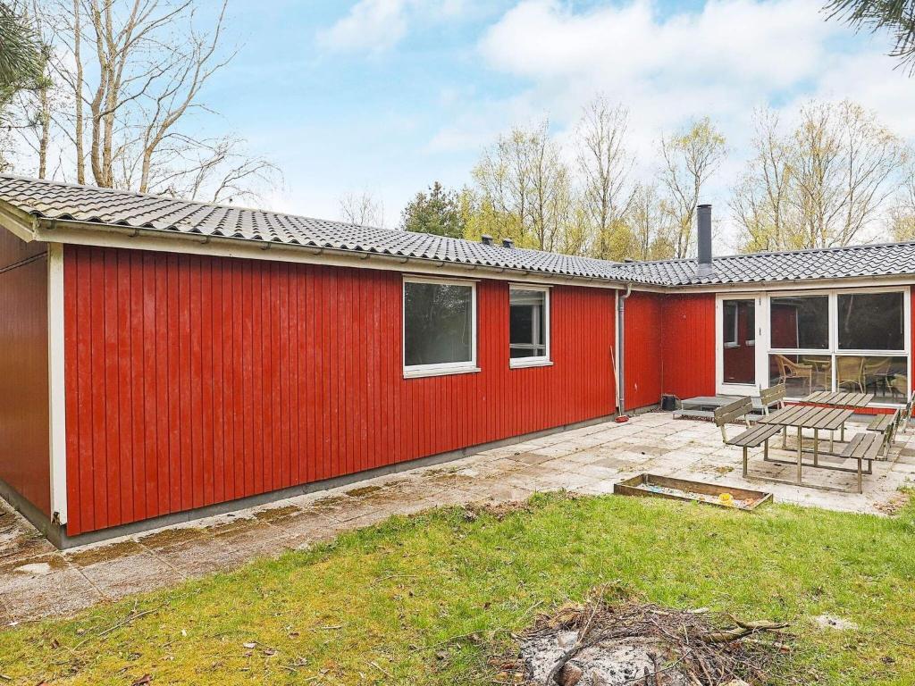 een rood huis met een patio in de tuin bij Ten-Bedroom Holiday home in Øster Assels in Sillerslev