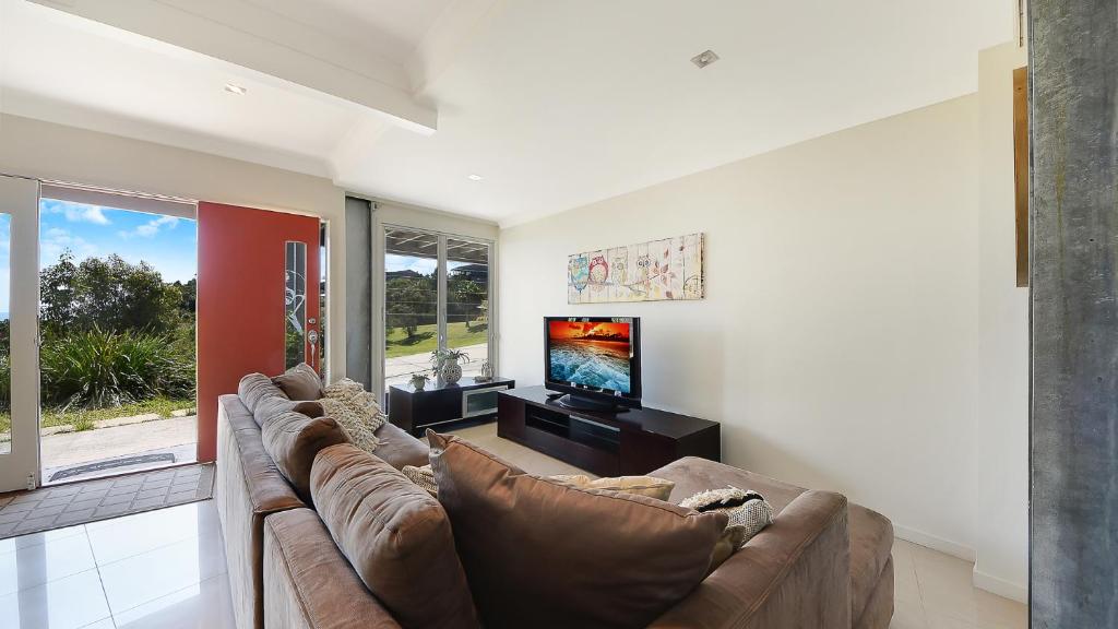 sala de estar con sofá y TV de pantalla plana en Ohana Beach House, en Tangalooma