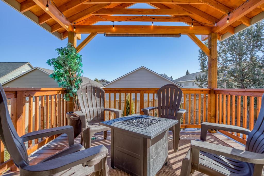a deck with chairs and a grill and a wooden pergola at East Bend Beauty in Bend
