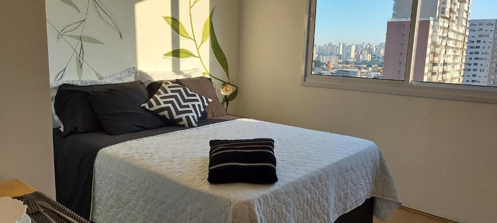 ein Schlafzimmer mit einem Bett mit einer weißen Bettdecke und einem Fenster in der Unterkunft Studio - O seu melhor lugar no Brás 200 Mts Metrô in São Paulo