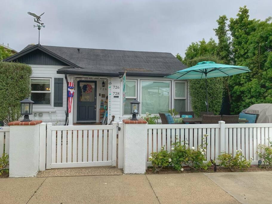 uma casa com uma cerca branca e um guarda-chuva em CUTE HOME 7 BLOCKS TO BEACH . XBOX . BIKES . PETS em Huntington Beach