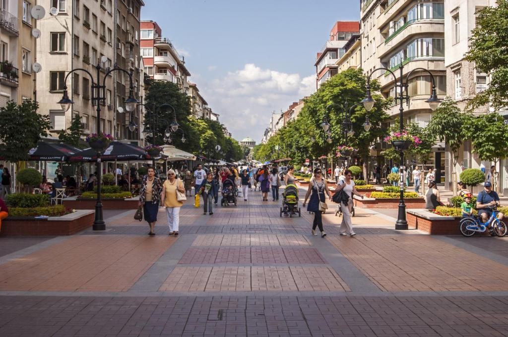 a group of people walking down a city street at St. George Hotel in Sofia