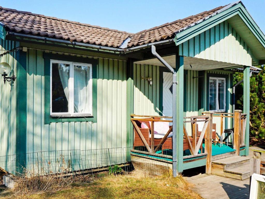 ein grünes Haus mit einer Veranda und einem Fenster in der Unterkunft Holiday home TROSA in Trosa