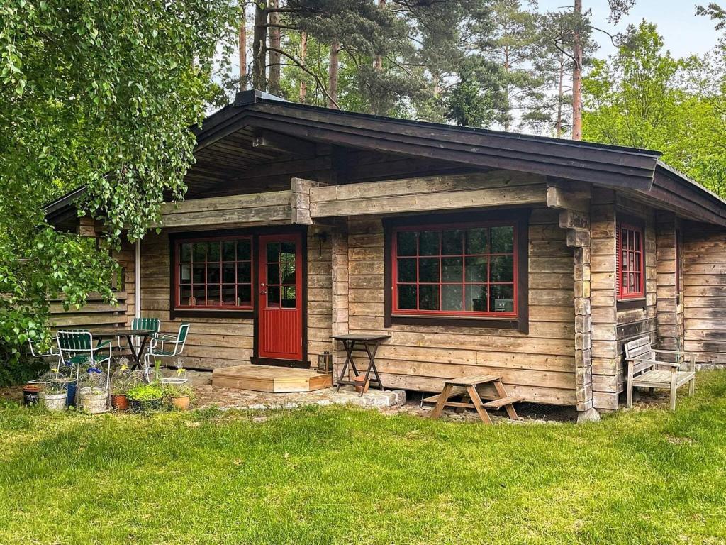 una piccola baita di tronchi con una porta rossa e un tavolo da picnic. di Holiday home blentarp II a Blentarp