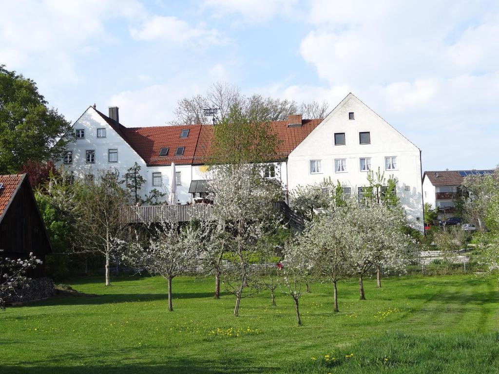 ein großes weißes Haus mit Bäumen im Hof in der Unterkunft Hörger Biohotel und Tafernwirtschaft in Kranzberg