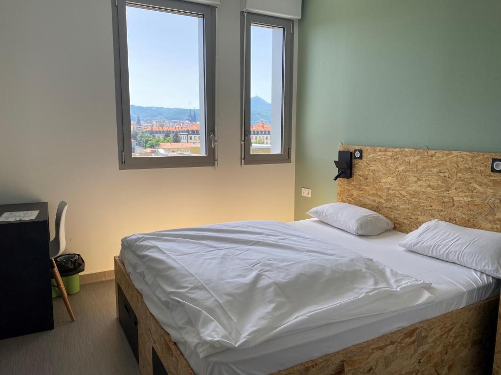 - une chambre avec un grand lit et 2 fenêtres dans l'établissement Auberge de jeunesse HI Clermont-Ferrand, à Clermont-Ferrand