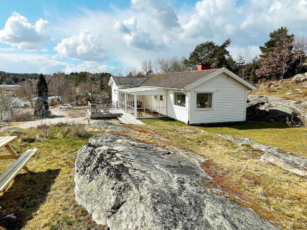 una casa blanca en una colina con una gran roca en Holiday home Hjälteby IV en Hjälteby