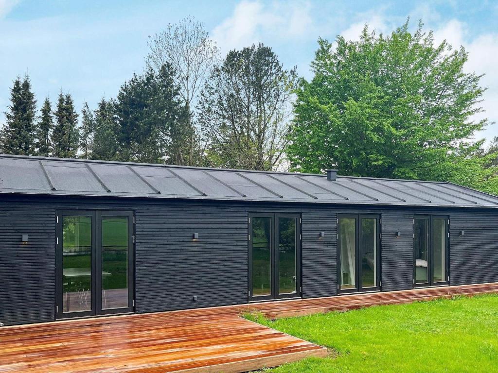 ein schwarzes modulares Haus mit einer Holzterrasse in der Unterkunft 6 person holiday home in Gilleleje-By Traum in Gilleleje
