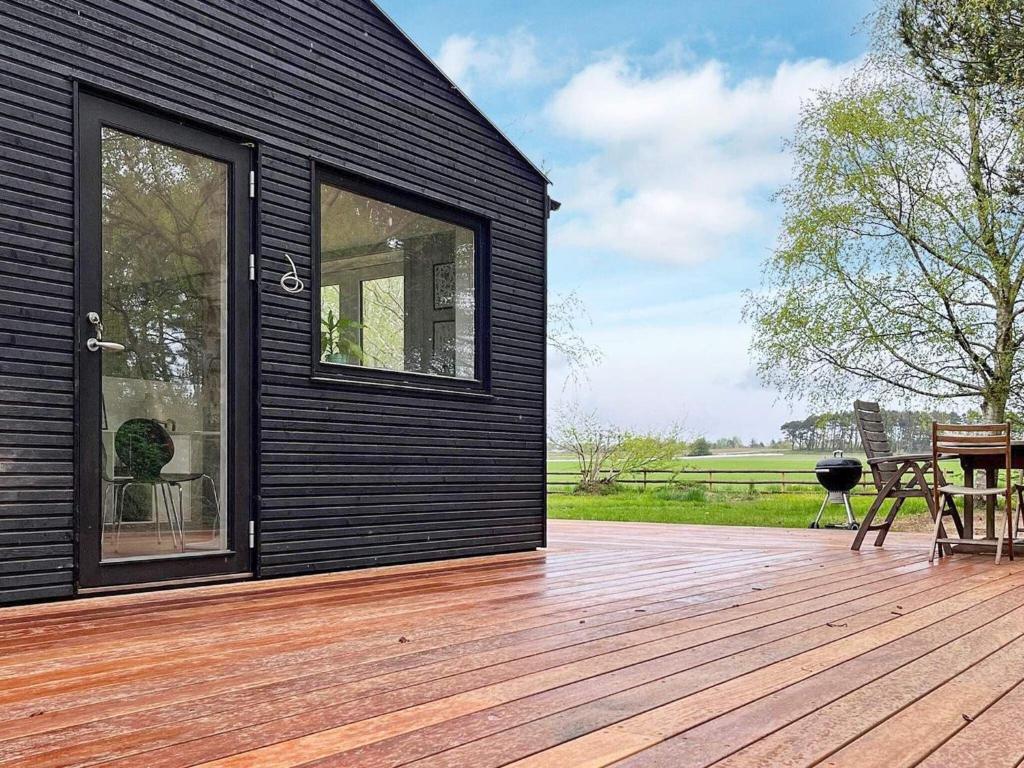 a black house with a wooden deck with a patio at Holiday home Gilleleje LXXXIII in Gilleleje