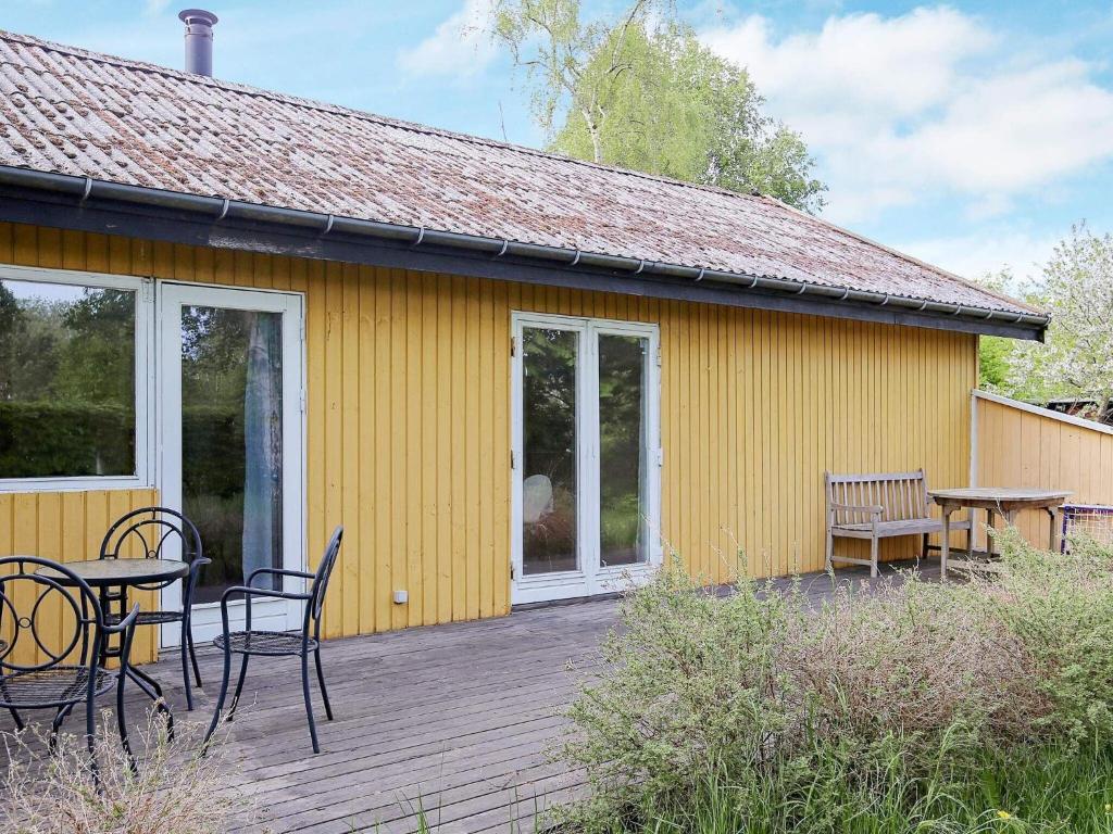una casa amarilla con una mesa y sillas en una terraza en Holiday home Højby XXXIII, en Højby