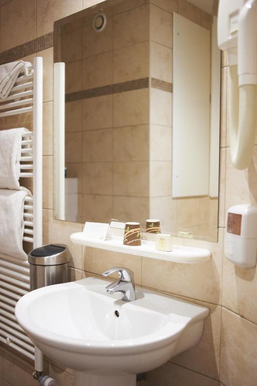 a bathroom with a sink and a mirror at Logis Hôtel Duquesne in Nantes